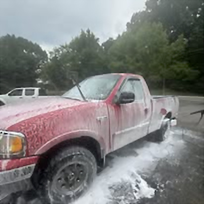 Red pickup covered in soap during a mobile wash